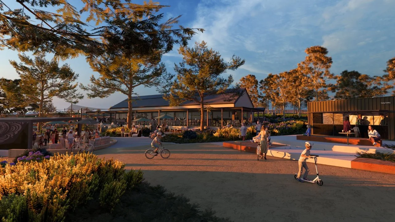 Outdoor café seating with people relaxing under umbrellas, surrounded by trees and coastal planting.