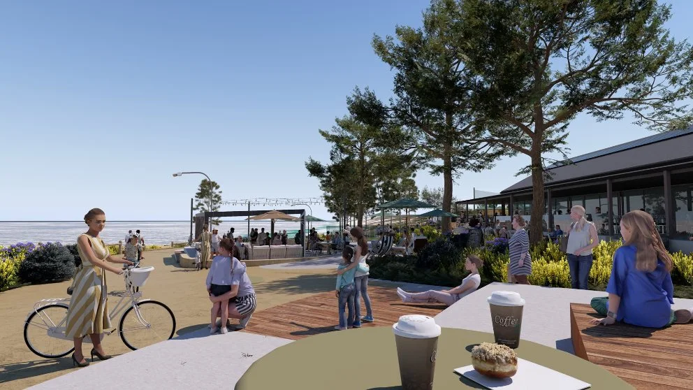 Families and visitors enjoying a café plaza near the beach, with seating, trees and coastal views.