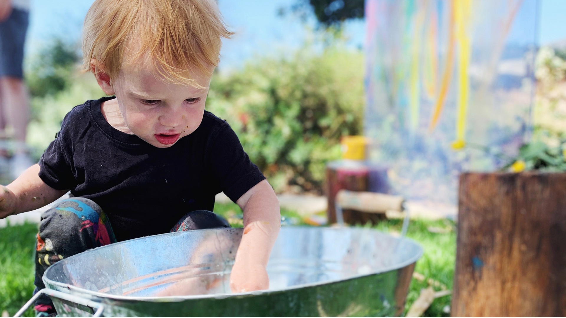 Toddler playing with items in a bucket
