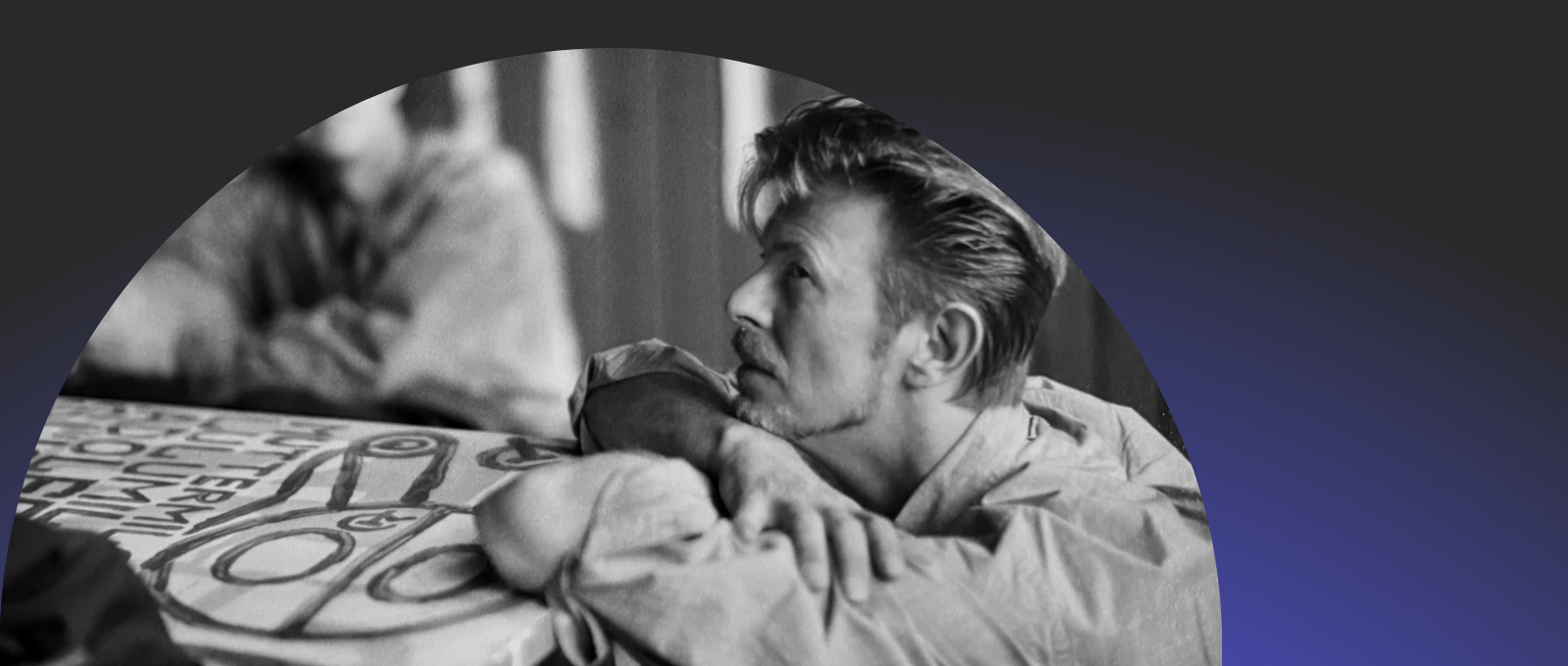 Young David Bowie with arms folded, looking at something off-camera