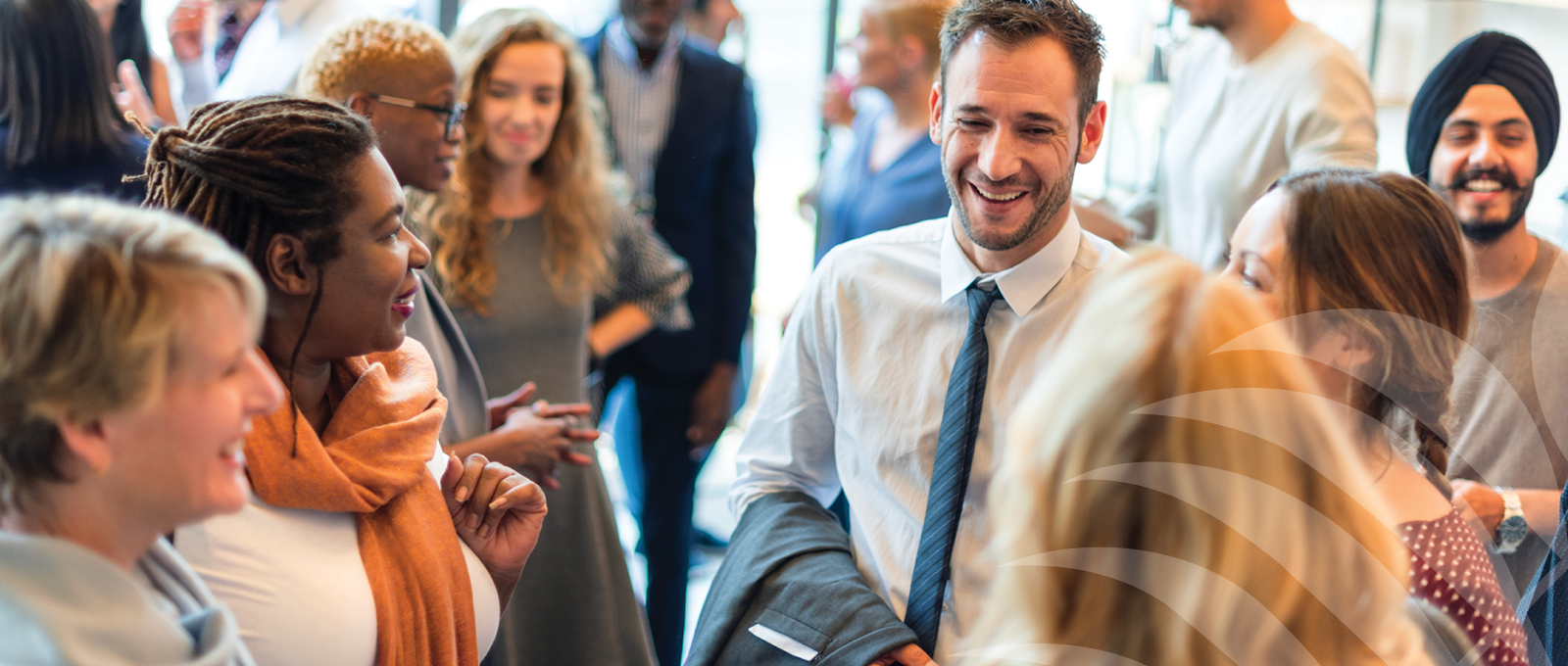 Diverse group of people networking and chatting at a community or professional event indoors.