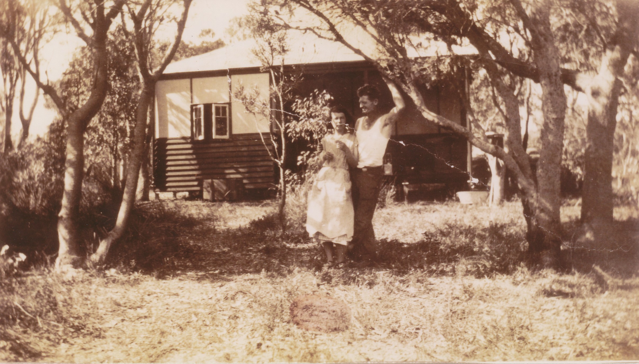 Sepia photo of man and lady standing in front of old house
