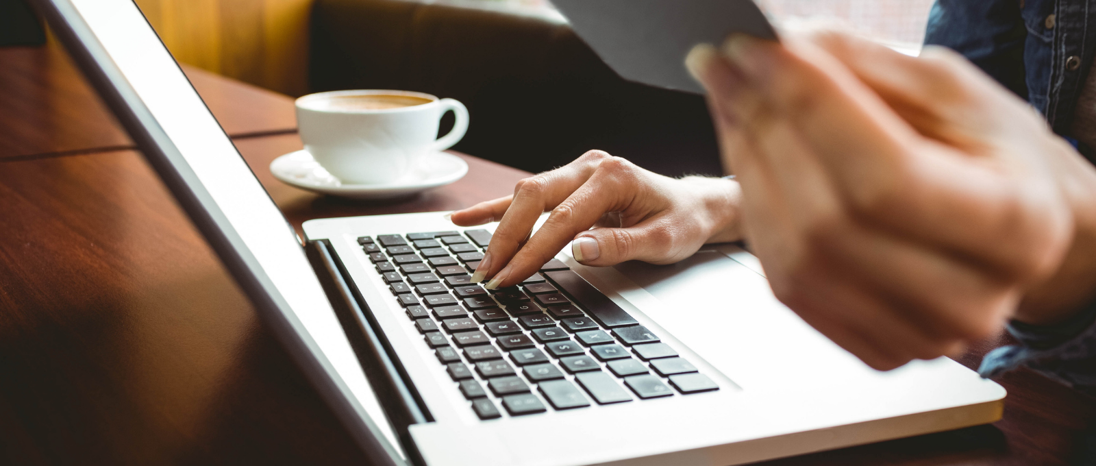 Lady holding a credit card sitting in front of a laptop