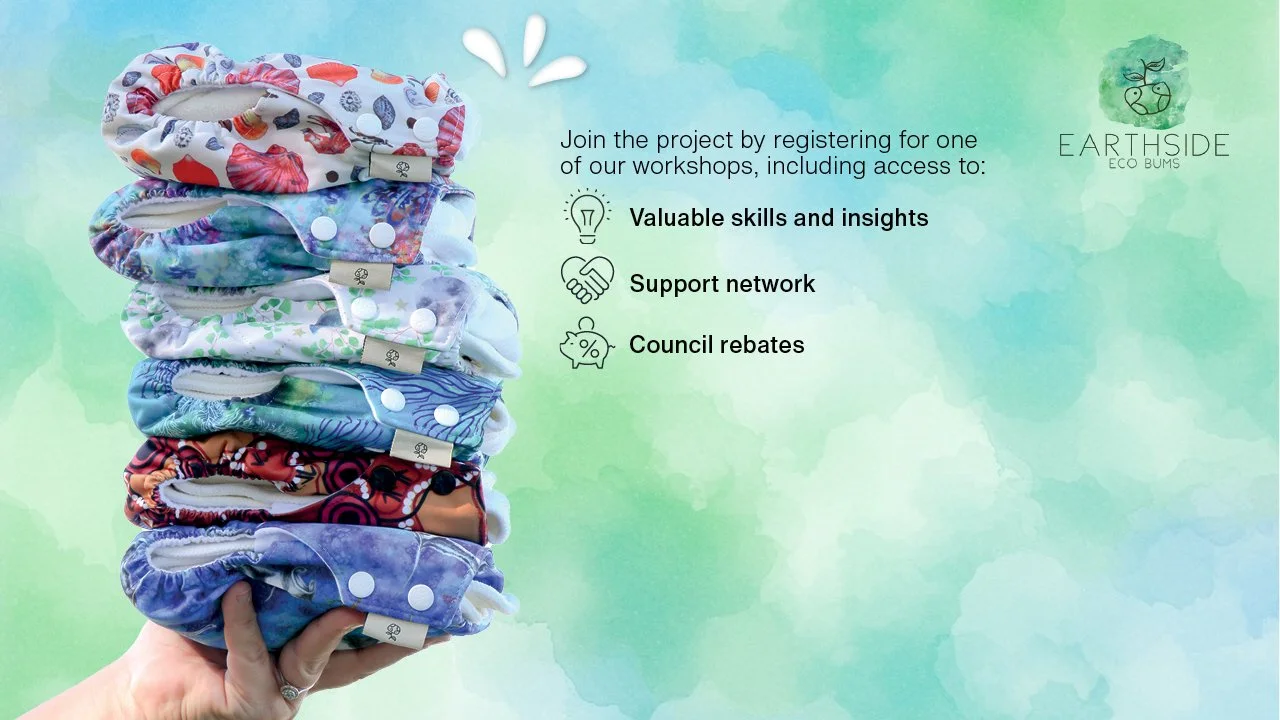 A hand holds a stack of colorful, reusable nappies against a soft green-blue watercolor background