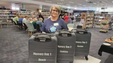 Lady standing in front of three black suitcases or memory bags