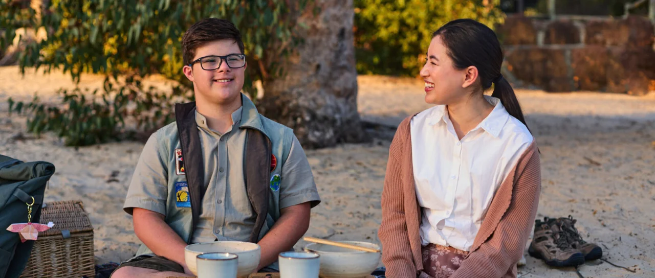Two people sitting on the beach with a picnic