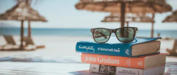 Stack of books on table with beach in the background