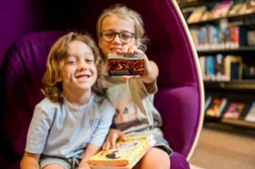 Two children sitting in purple egg chair