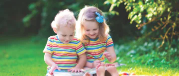 Two children reading books in the park