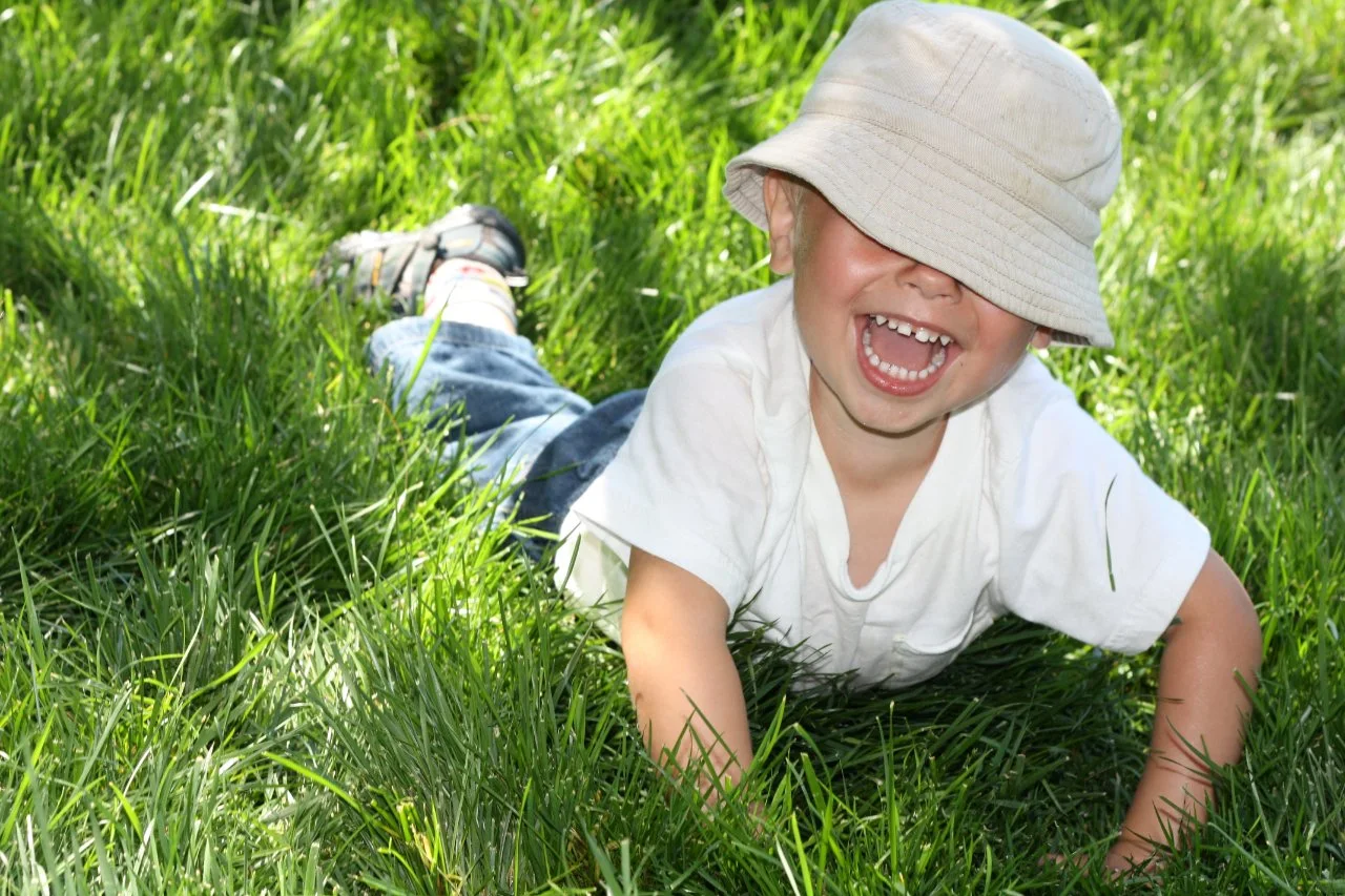 Young child with a white hat sitting in a park
