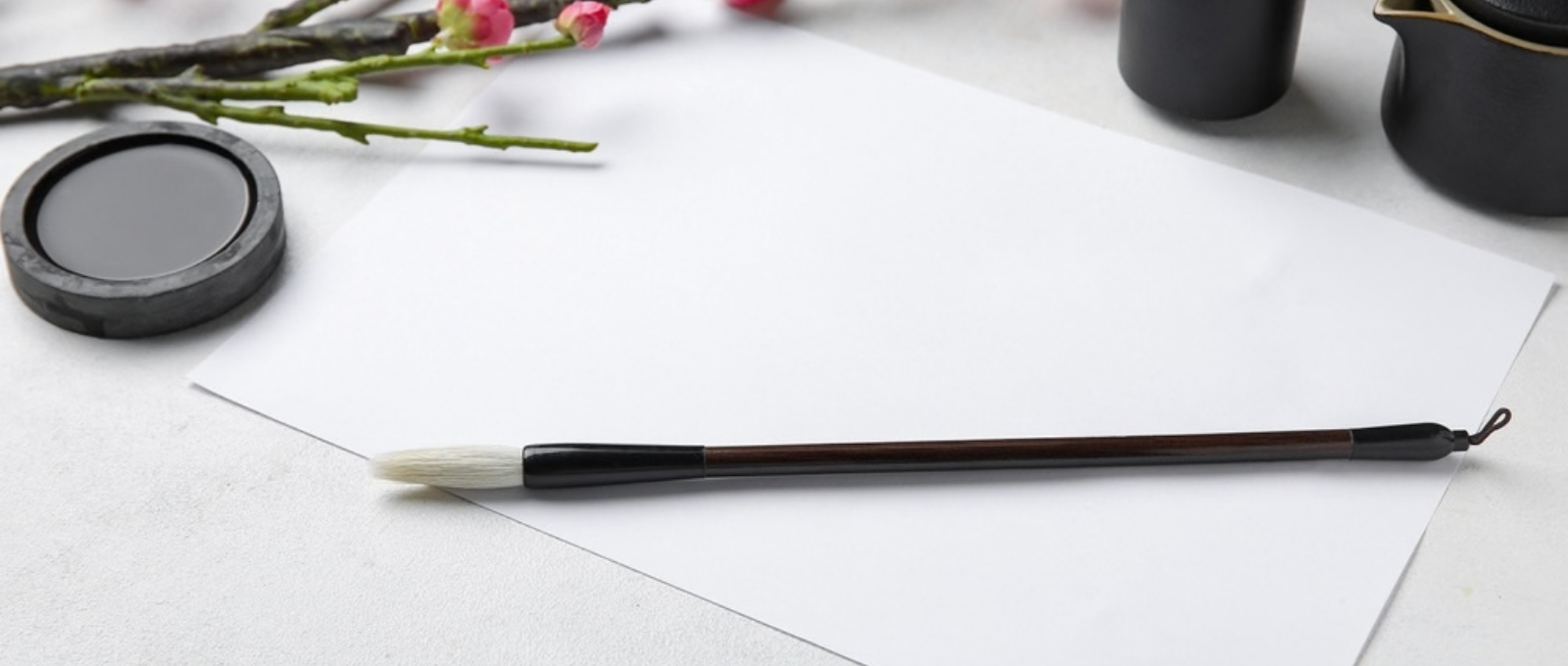 Paintbrush and paper with flower in the background