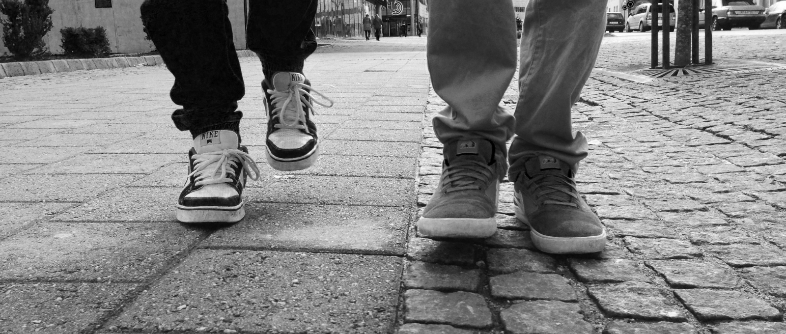 Black and white image of feet of two people walking on pavers
