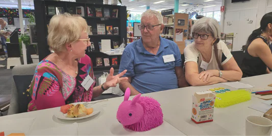 Three seniors talking in a library